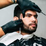 Man receiving a precise beard trim in a barbershop, showcasing expert grooming skills.